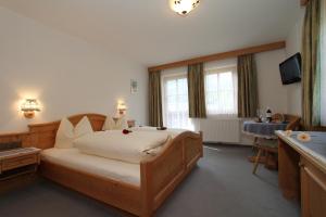 a bedroom with a large bed and a television at Hotel - Wirts'haus "Zum Schweizer" in Lofer