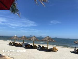 een strand met stoelen en parasols en de oceaan bij Old Town Hotel in Hội An