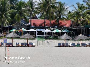 una spiaggia con sedie e ombrelloni sulla sabbia di Old Town Hotel a Hoi An