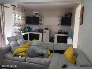 a living room with a gray couch with yellow pillows at kire homes in Nakuru
