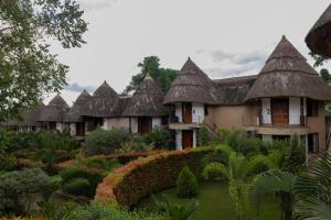 a row of cottages with thatched roofs at Forest Park Resort in Buloba