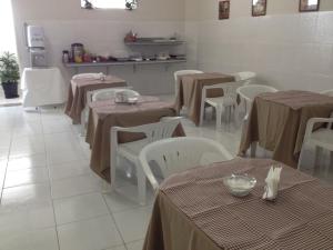 a dining room with tables and white chairs and tablesearcher at BLUES HOTEL in Guaratinguetá