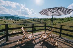 two chairs and an umbrella on a wooden deck at Cloud9 Glamping Žabljak in Žabljak
