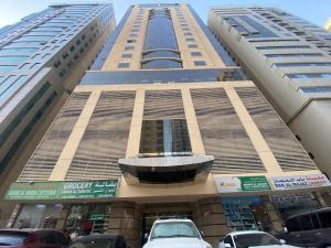 un grande edificio con auto parcheggiate di fronte di سكن شباب بالتعاون - ALEX Hostel - Sharjah a Sharjah