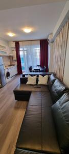 a living room with a black leather couch at Monaco Summerland Rentals in Mamaia