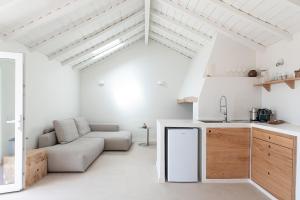 a white kitchen and living room with a couch at Barranquinho in Santiago do Cacém