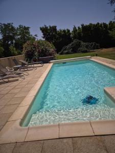 a swimming pool filled with blue water next to chairs at EPICEAH Loft à la campagne à 10 mn de Valence in Valence