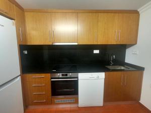 a kitchen with a black counter top and wooden cabinets at Quinta do José - AL in Praia da Vitória +8 photos