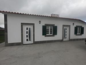 a white house with two green shuttered windows at Quinta do José - AL in Praia da Vitória