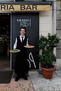 a man in a tuxedo holding two plates of pizza at La Terrazza sull'Arena in Verona