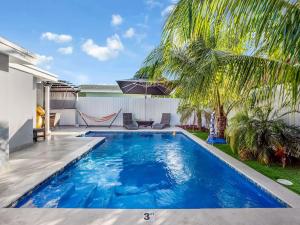 a swimming pool in the backyard of a house with a palm tree at Luxury Villa with Heated Pool, Jaccuzzi, Gym, Games and More in Miami Gardens