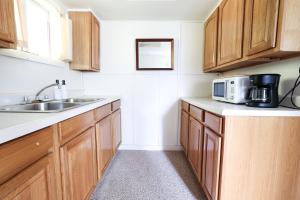 una cucina con armadi in legno, lavandino e forno a microonde di Wilderness West Resort Cabin 3 a Colville Altre 16 foto