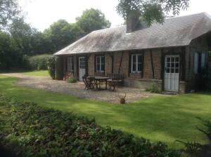 a brick house with a picnic table in the yard at Charmante Petite Maison dans le Jardin in Letteguives