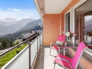 a balcony with pink chairs and a table with a view at Apartment Promenade Apt 109 & Apt 110 by Interhome in Arosa