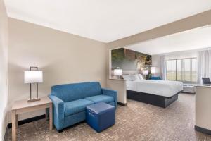 Una habitación de hotel con una cama y una silla azul. en Clarion Pointe Sioux Falls Airport, en Sioux Falls