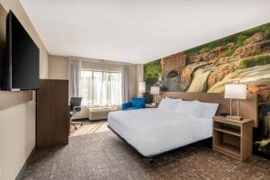 a hotel room with a bed and a painting on the wall at Clarion Pointe Sioux Falls Airport in Sioux Falls