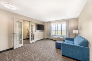 a living room with a blue couch and a window at Clarion Pointe Sioux Falls Airport in Sioux Falls