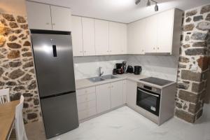a kitchen with white cabinets and a stainless steel refrigerator at Elysian Stone Apartment I in Litochoro