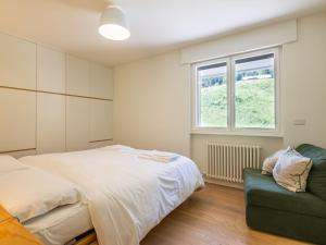 a bedroom with a bed and a green couch at Apartment Enrosadira-13 by Interhome in Alba di Canazei