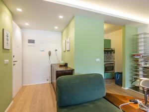 a living room with a green chair and a kitchen at Apartment Enrosadira-13 by Interhome in Alba di Canazei