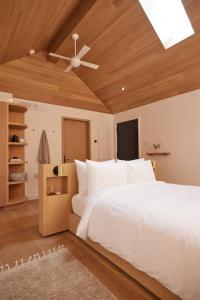 a bedroom with a white bed and a ceiling fan at Serenity by the Lake at Dimensions - Cabin Three in Algonquin Highlands