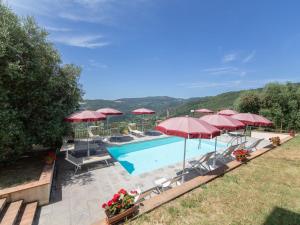a swimming pool with red umbrellas and chairs at Apartment Antico Loggiato-3 by Interhome in Pontassieve