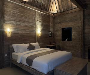 a bedroom with a large bed and a television at Umaloka Eco Villa in Tirtagangga