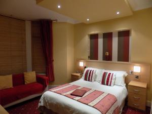 Una habitación de hotel con una cama y un sofá rojo. en The Norwood, en Blackpool