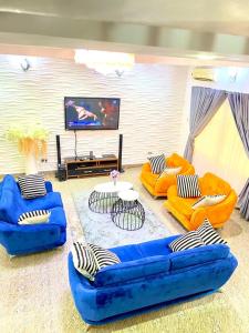a living room with three blue couches and a flat screen tv at Chevy in Lekki