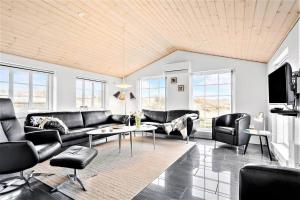 a living room with black leather furniture and windows at 362-Hvide-Sande-Fyrmarken-35 in Hvide Sande