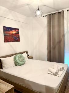 a bedroom with a bed with white sheets and a window at Pinelopi family Apartment in Hanioti