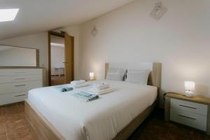 ein Schlafzimmer mit einem großen weißen Bett und einem Spiegel in der Unterkunft Best Houses 47 - Consolação Beach House in Atouguia da Baleia