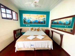 a bedroom with a bed with a painting on the wall at Pousada Vison Ubatuba - Praia Grande in Ubatuba