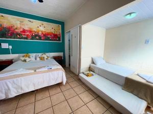 a bedroom with two beds and a painting on the wall at Pousada Vison Ubatuba - Praia Grande in Ubatuba