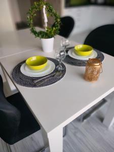 a white table with two plates and yellow dishes on it at Comfy Studio in Rzeszów