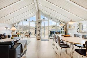 a dining room and living room with a table and chairs at 555-Hvide-Sande-Tornbjerrevej-32 in Havrvig