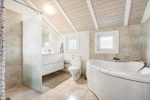a bathroom with a tub and a toilet and a sink at 555-Hvide-Sande-Tornbjerrevej-32 in Havrvig