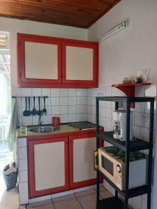 a kitchen with red cabinets and a microwave at Appartement moderne avec vue mer à Le Vauclin, 55 m² in Le Vauclin