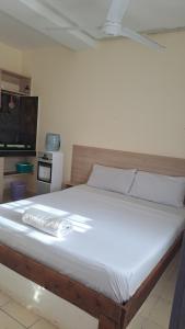 cama blanca grande con mando a distancia en Diani Savanna Sunset Studio Apartment, en Diani Beach
