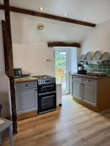 a kitchen with a stove top oven in a room at Titmouse at Trenale Court Cottages in Tintagel +18 photos
