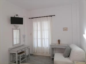 a white living room with a white couch and a mirror at Nikoleta's Studios in Drios