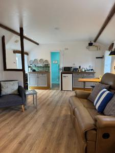 a living room with a couch and a kitchen at Titmouse at Trenale Court Cottages in Tintagel