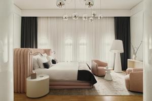 a bedroom with a bed and a chair and a chandelier at Hotel Blow Up Hall in Poznań