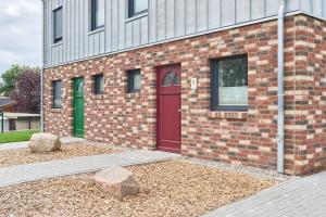 ハーフクルークにあるHaffhaus 13c Kapitänskajüteの赤いドアと岩のあるレンガ造りの建物