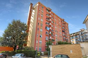 a tall orange building with cars parked in front of it at Casa Torino - Rho Fiera Stay in Rho