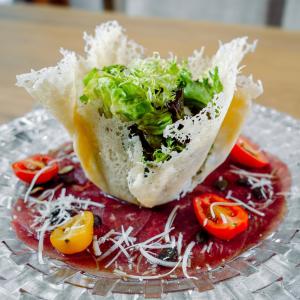a sandwich with lettuce and tomatoes on a glass plate at Gartenhotel Maria Theresia in Hall in Tirol