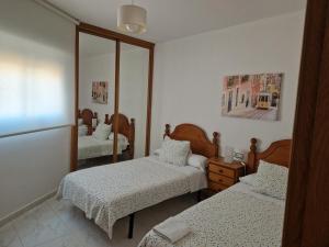 sypialnia z dwoma łóżkami i lustrem w obiekcie APARTAMENTOS PASEO DE LORDELO - 2 Izquierda w mieście O Grove