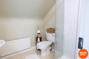 a bathroom with a toilet with a doll next to it at Heartbeat Cottage in Letterkenny +5 photos