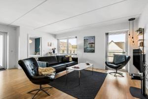 sala de estar con sofá de cuero negro y 2 sillas en 794-Hvide-Sande-Strandgade-6-Lejl-5, en Hvide Sande