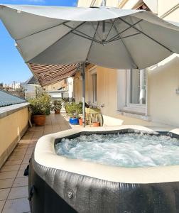 einen Whirlpool mit Sonnenschirm auf einer Terrasse in der Unterkunft Charmante chambre chez l'habitant pour 2 personnes- parking couvert in Le Mans